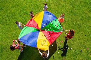 Group bouncing balls on a colorful parachute outside