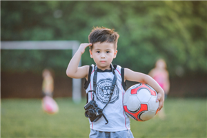 A Young Saluting Boy Holding A Soccer Ball On The Field